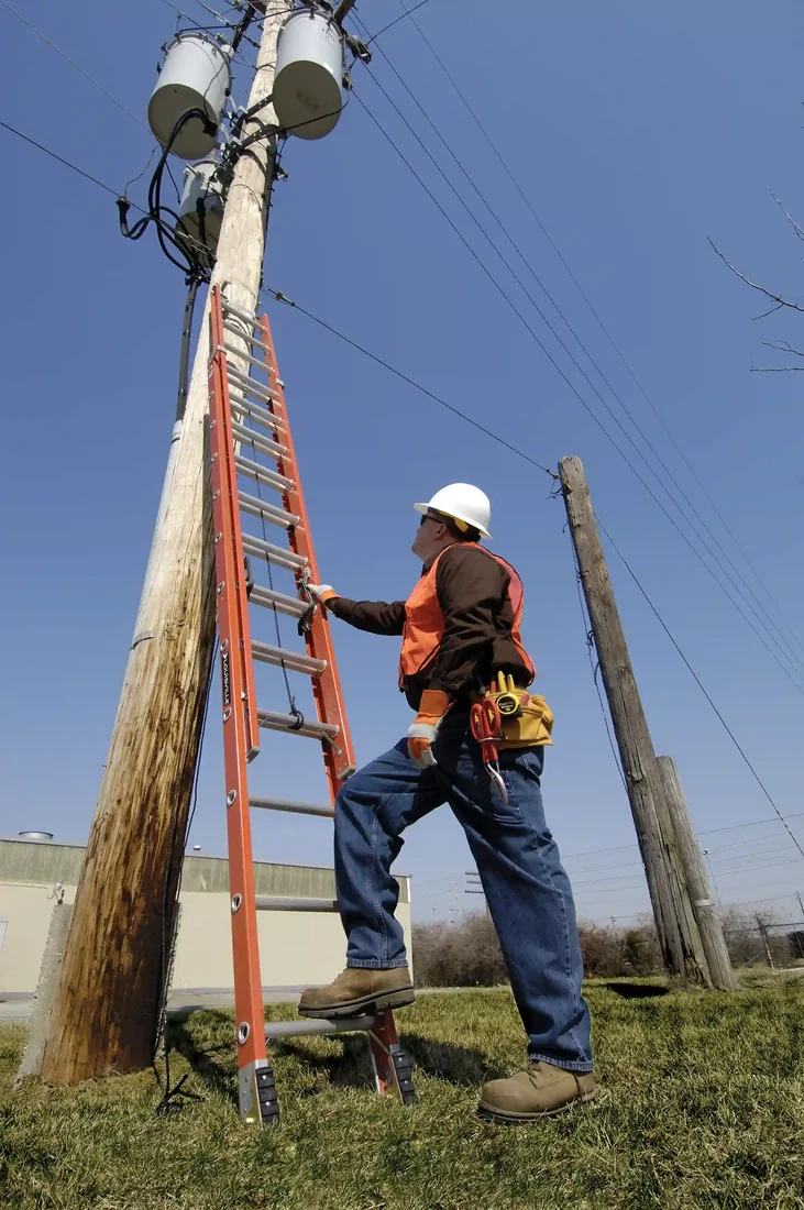 Worker climbing a Louisville Ladder fiberglass extension ladder on a job site
