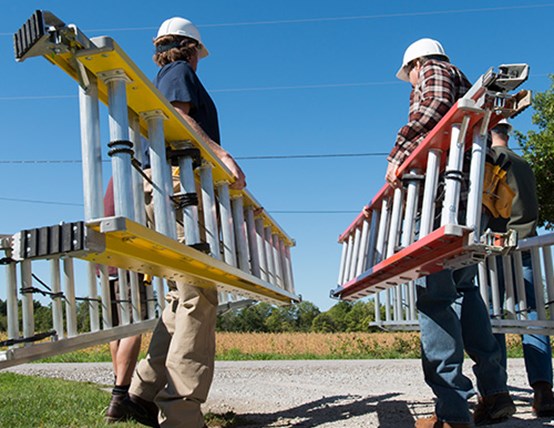 Image of four construction workers walking away each carrying a Louisville Ladder brand extension ladder
