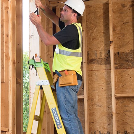 Man working with electrical wiring while standing on a Fiberglass Ladder