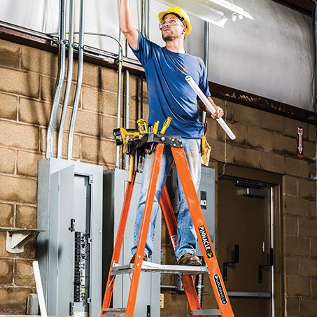 Man installing lighting while standing on a platform ladder